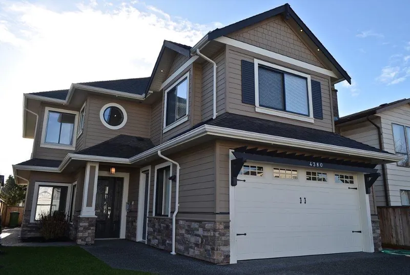 A finished custom home in shingle and stone with a round accent window over the garage.