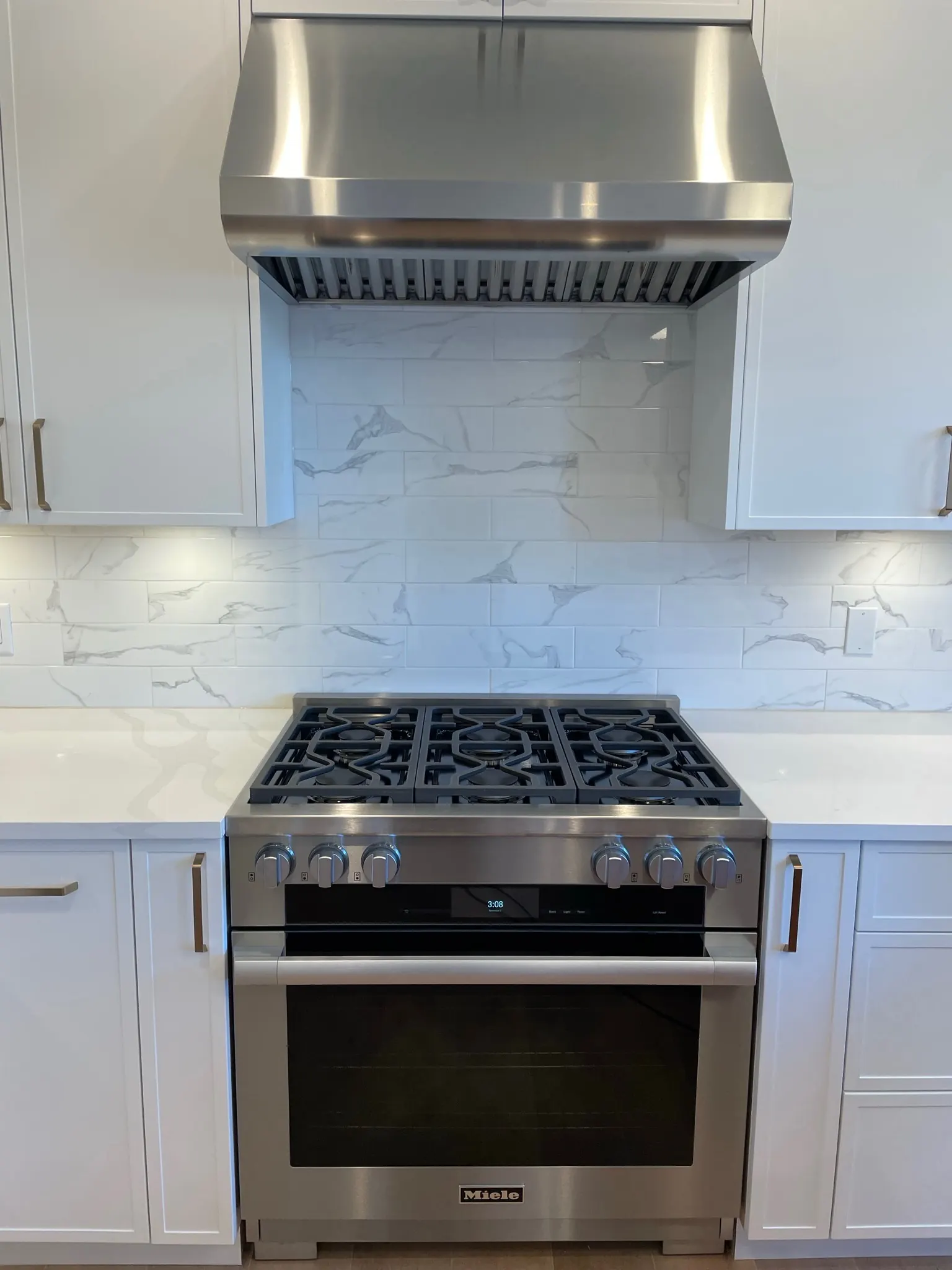 A finished kitchen: the range wall, the hood run and the slab backsplash behind it.