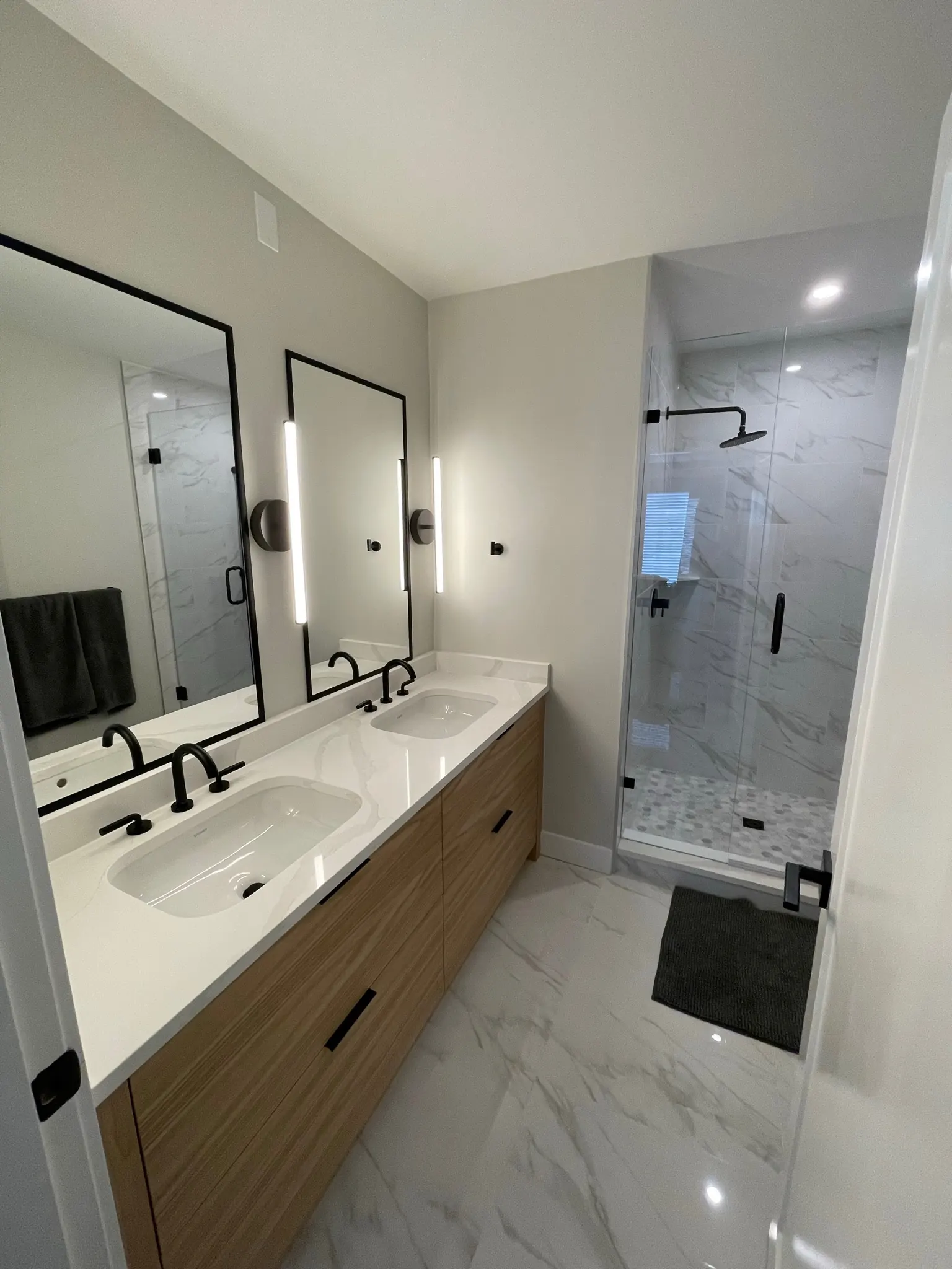 A finished main bathroom — double vanity, wall-hung taps, full-height tile.