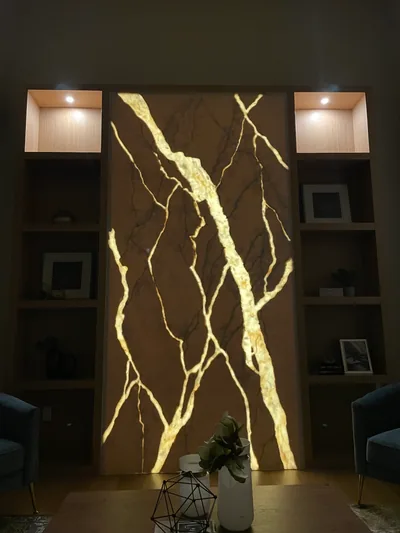 A backlit stone feature wall glowing between built-in shelving in a finished living space.