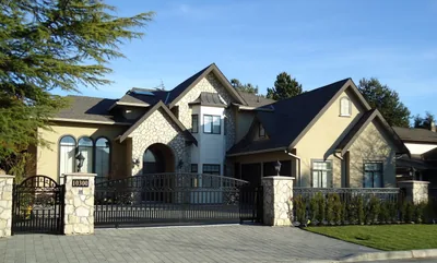 A large stone and stucco custom home behind its own gates, the full front elevation and both gables in one frame.
