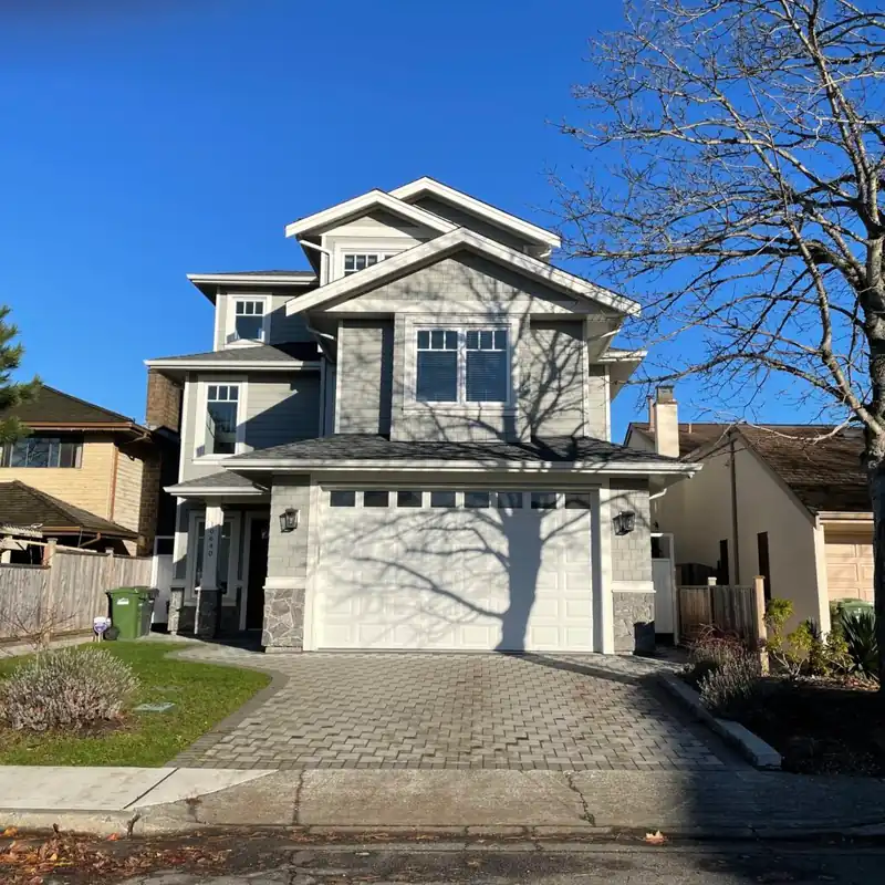 A finished craftsman-style custom home with a white gabled front and a paver driveway.