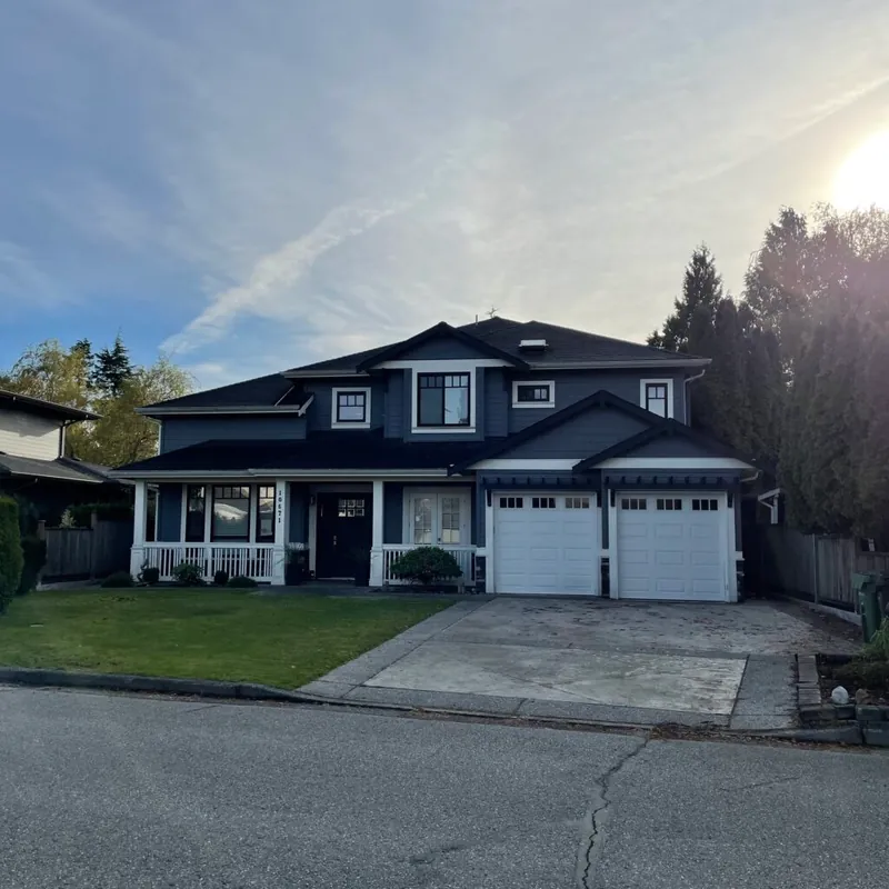 A finished custom home with a deep covered porch, twin garages and a lawn frontage.